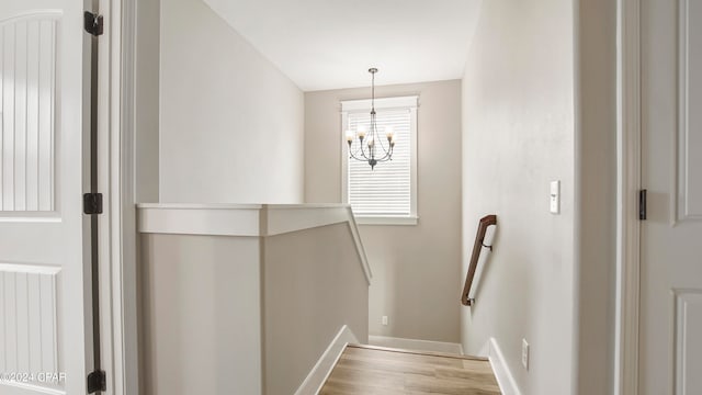 stairway with an inviting chandelier and wood-type flooring