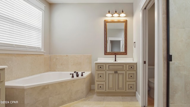 bathroom with tile patterned flooring, tiled tub, vanity, and toilet