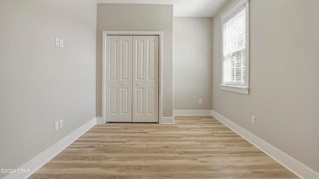 unfurnished bedroom with a closet and light hardwood / wood-style floors