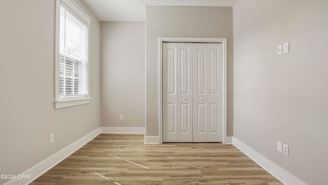 unfurnished bedroom with light hardwood / wood-style flooring and a closet