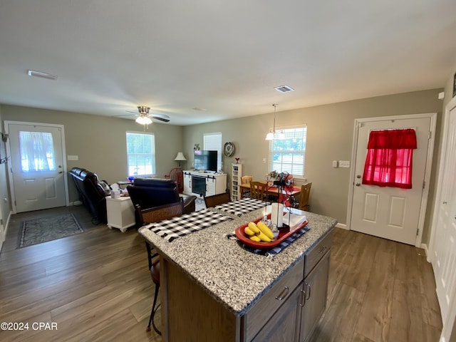 kitchen featuring ceiling fan, dark hardwood / wood-style flooring, a kitchen island, and hanging light fixtures