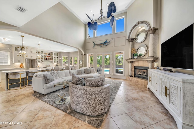 tiled living room with sink, a towering ceiling, a chandelier, and a tile fireplace