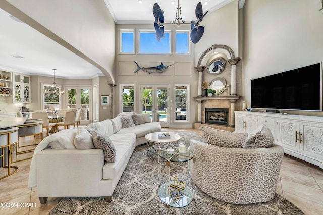 living room featuring a large fireplace, a wealth of natural light, a notable chandelier, and french doors