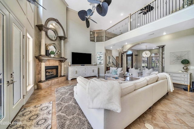 living room featuring ceiling fan with notable chandelier, a high ceiling, and a tile fireplace