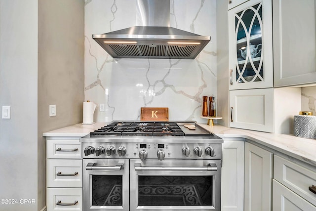 kitchen with white cabinets, backsplash, double oven range, and wall chimney exhaust hood