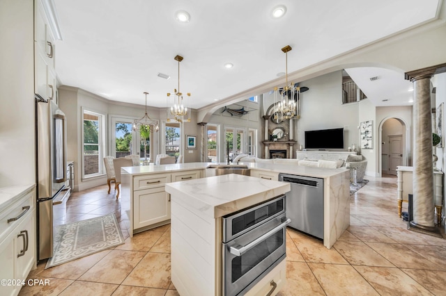 kitchen with white cabinets, a kitchen island, a chandelier, and appliances with stainless steel finishes