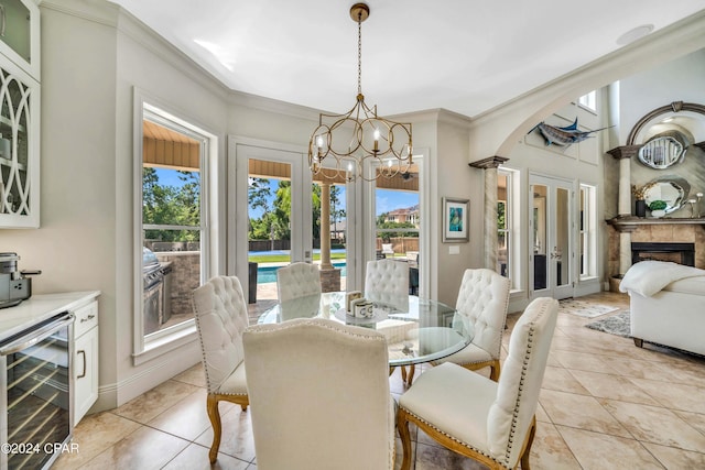 tiled dining space with a chandelier, ornamental molding, beverage cooler, and plenty of natural light