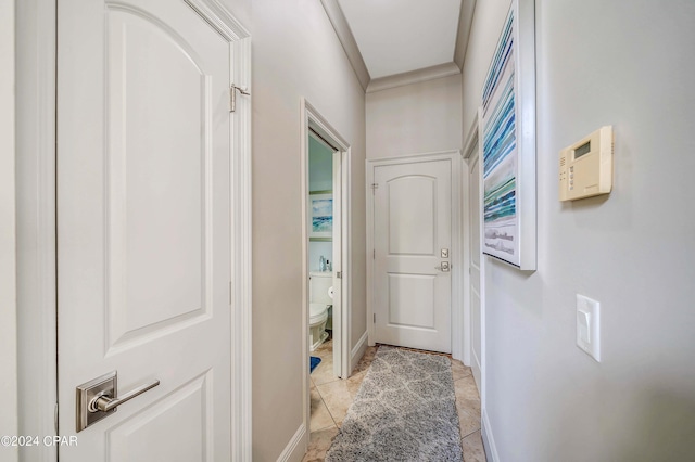 hallway with ornamental molding and light tile patterned floors