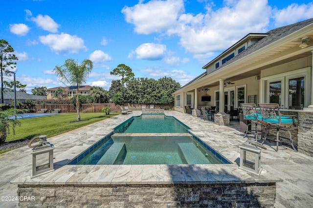 view of swimming pool with an in ground hot tub, a lawn, exterior bar, ceiling fan, and a patio area