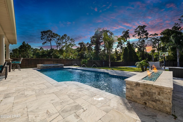 pool at dusk with a fire pit, an in ground hot tub, a patio area, and pool water feature