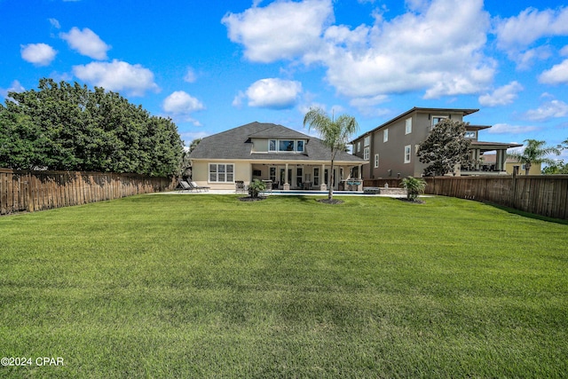 back of property featuring a pool, a lawn, and a patio