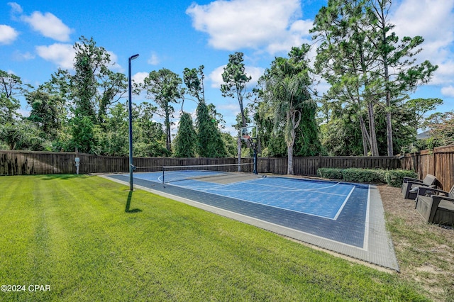 view of tennis court featuring basketball hoop and a lawn