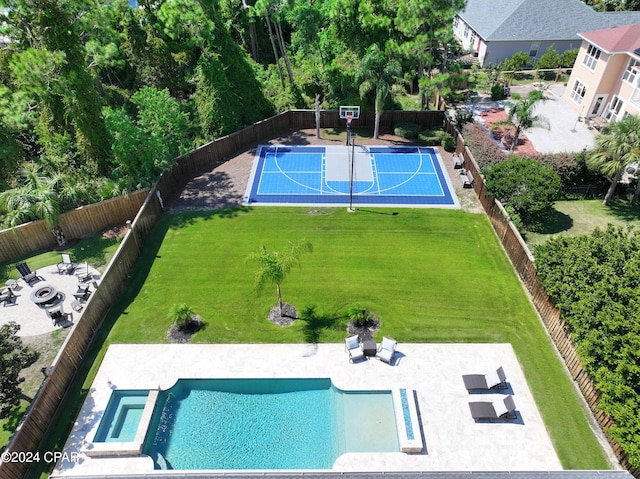 view of swimming pool featuring basketball hoop, an outdoor fire pit, and a yard