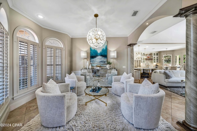 tiled living room with decorative columns, sink, crown molding, and a notable chandelier