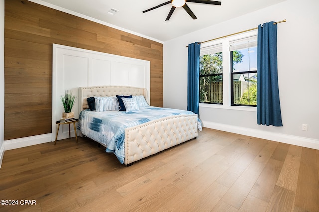 bedroom with wooden walls, ceiling fan, and hardwood / wood-style flooring