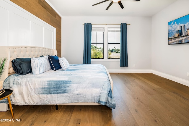 bedroom with ceiling fan, hardwood / wood-style flooring, and wood walls