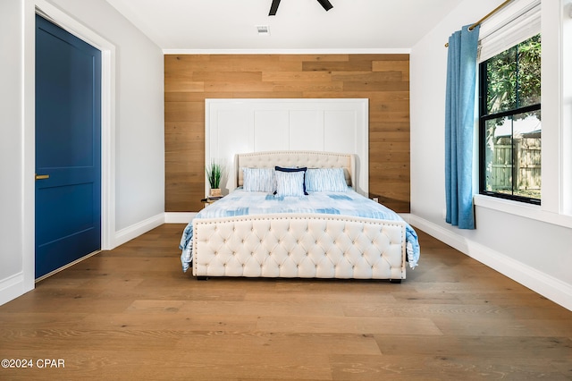 bedroom with ceiling fan, hardwood / wood-style flooring, and wood walls