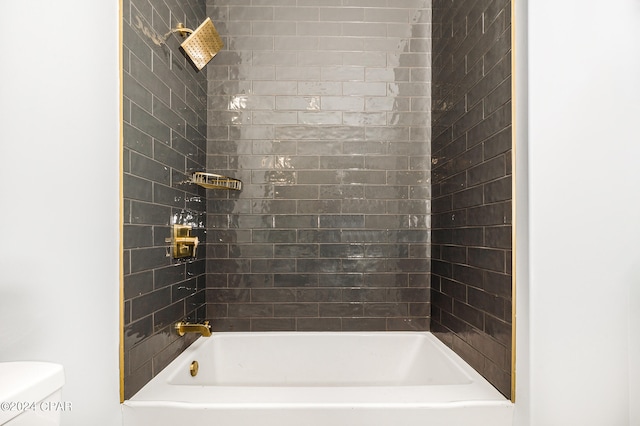 bathroom featuring tiled shower / bath combo and toilet