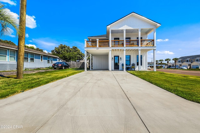 view of front of home with a balcony, a front yard, and a carport