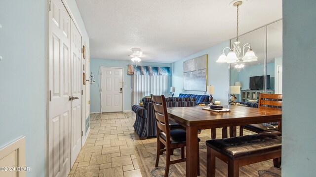 dining space with ceiling fan with notable chandelier and a textured ceiling