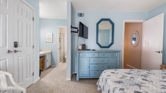 carpeted bedroom with ensuite bath, a textured ceiling, and a closet