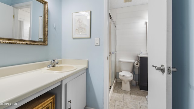 bathroom featuring a shower stall, stone finish floor, toilet, vanity, and baseboards