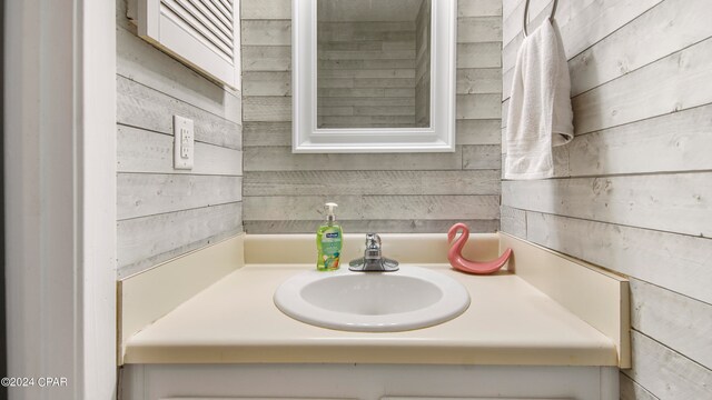 bathroom featuring vanity and wooden walls