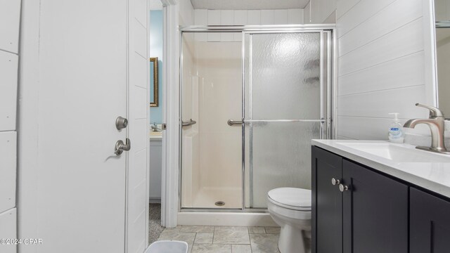 bathroom featuring vanity, walk in shower, tile patterned flooring, and toilet