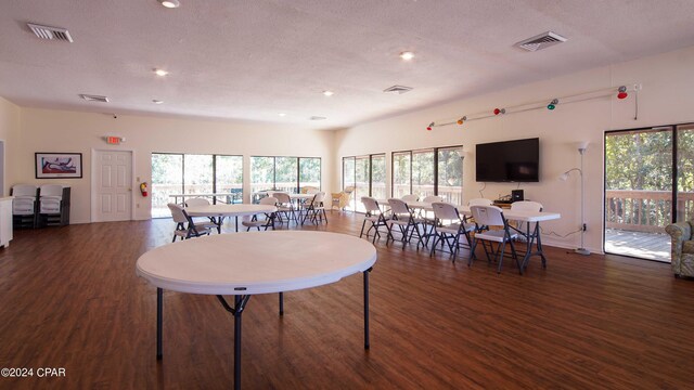 dining space with dark wood-type flooring, a healthy amount of sunlight, and a textured ceiling