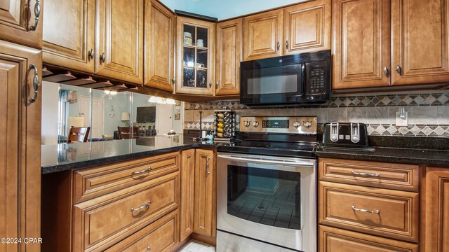 kitchen featuring stainless steel range with electric stovetop, tasteful backsplash, and dark stone countertops