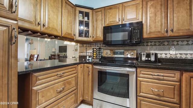 kitchen with brown cabinetry, decorative backsplash, black microwave, and electric stove