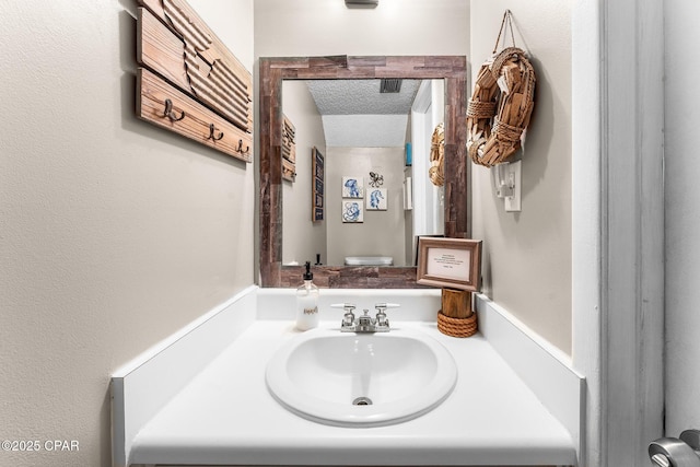 bathroom featuring vanity, toilet, and a textured ceiling