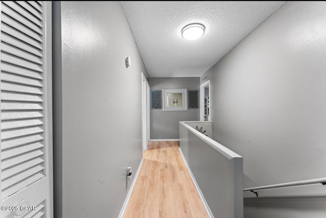 hall with light hardwood / wood-style floors and a textured ceiling