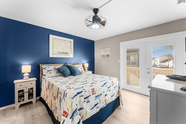 bedroom featuring a textured ceiling, light wood-type flooring, and french doors