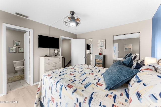 bedroom with ensuite bathroom, light tile patterned floors, and a closet