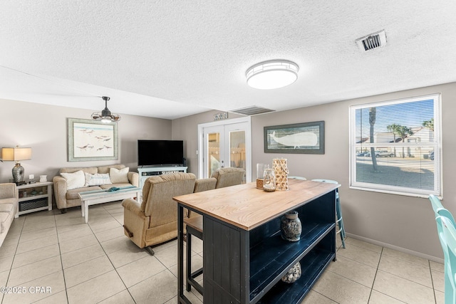 dining area with french doors, a textured ceiling, and light tile patterned floors