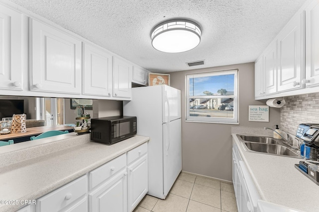 kitchen featuring sink, tasteful backsplash, light tile patterned floors, white refrigerator, and white cabinets