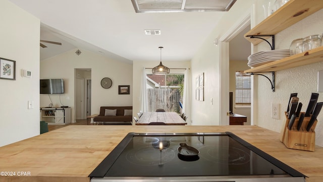 kitchen with wooden counters, wood-type flooring, decorative light fixtures, black stove, and vaulted ceiling