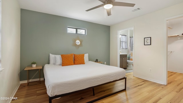 bedroom with ceiling fan, light wood-type flooring, ensuite bathroom, and a walk in closet