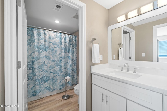 bathroom with walk in shower, hardwood / wood-style floors, vanity, and toilet