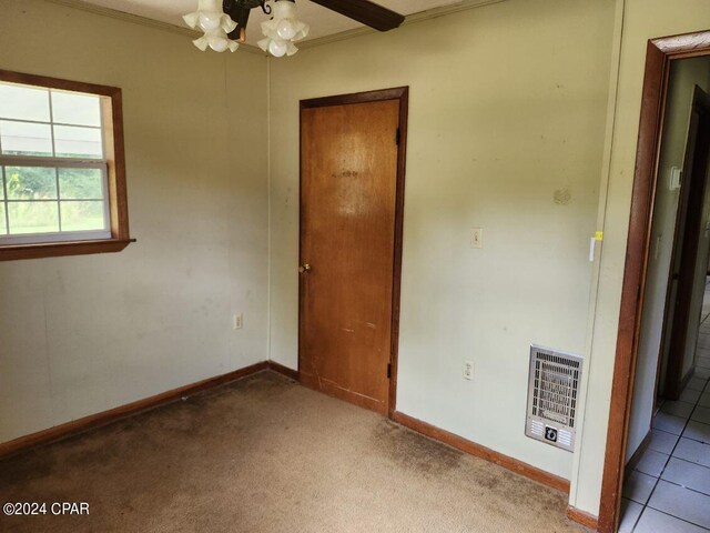 spare room with ceiling fan, heating unit, crown molding, and light carpet