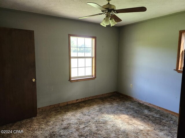 empty room with ceiling fan, a textured ceiling, ornamental molding, and carpet