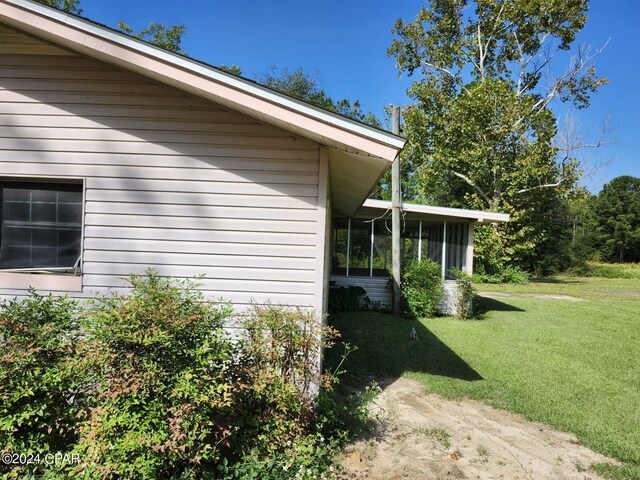 view of side of property with a lawn and a sunroom