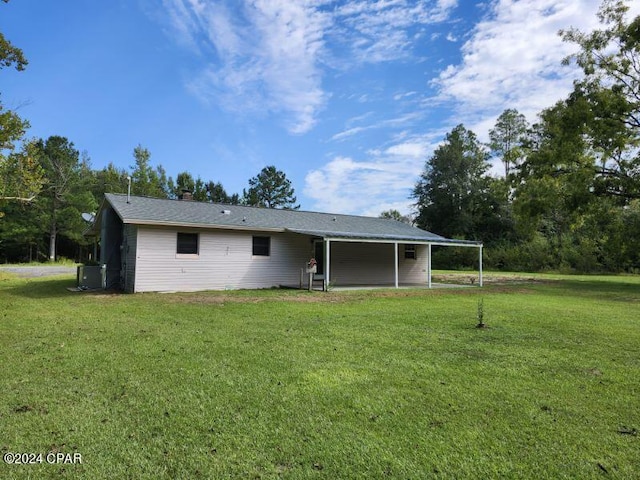 rear view of house featuring a lawn and central AC