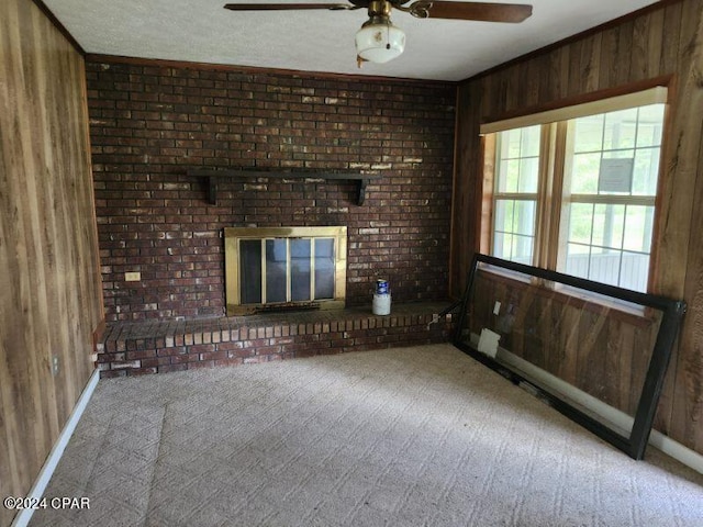 unfurnished living room featuring ceiling fan, wooden walls, crown molding, and carpet flooring