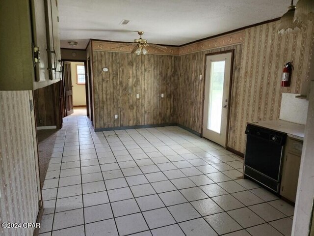 interior space with dishwasher, light tile patterned floors, ornamental molding, ceiling fan, and wooden walls