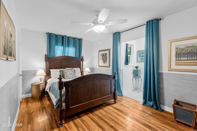 bedroom with tile walls, wood-type flooring, and ceiling fan