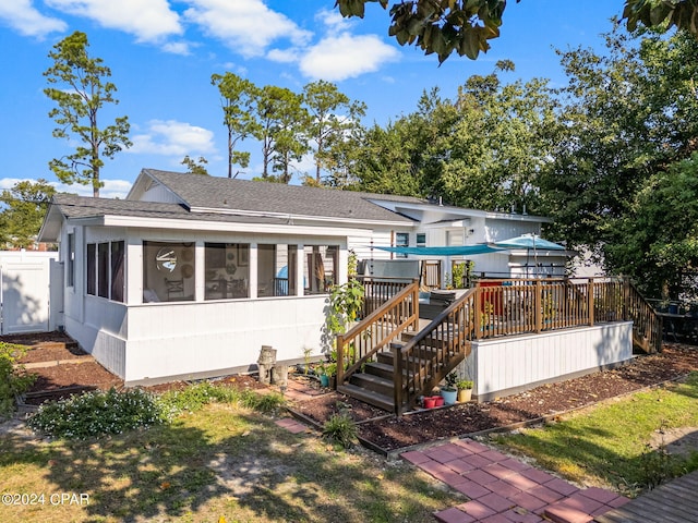 rear view of property featuring a wooden deck and a sunroom