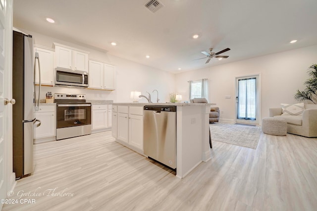 kitchen featuring light hardwood / wood-style flooring, a kitchen island with sink, appliances with stainless steel finishes, and white cabinetry