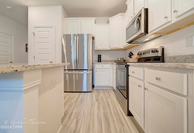 kitchen with appliances with stainless steel finishes, light wood-type flooring, light stone countertops, and white cabinets